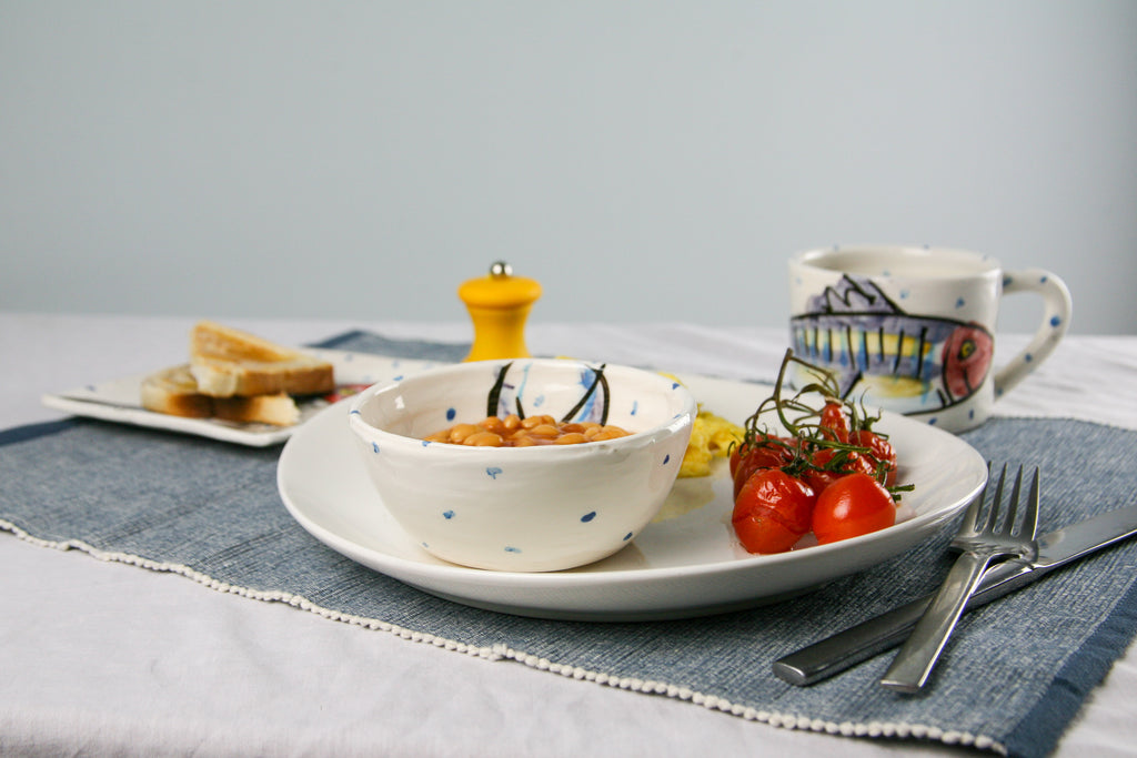 Showing how to use the ramekin bowl to serve beans in this case. It rests on a plate with roast tomatoes and eggs. In the background, a coordinating mug rests. A small plate is nearby with toast. Handmade in Ireland.