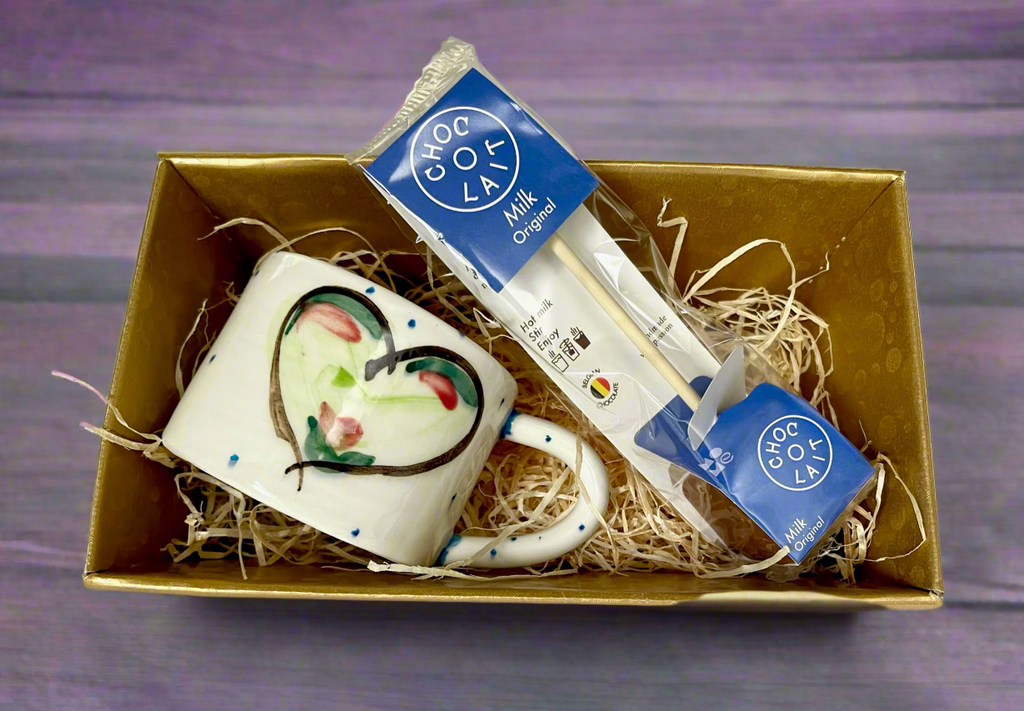 Affordable gift of one espresso mug, handmade and hand painted with delicious green hearts and a hot chocolate stirrer sitting in a gift box. 