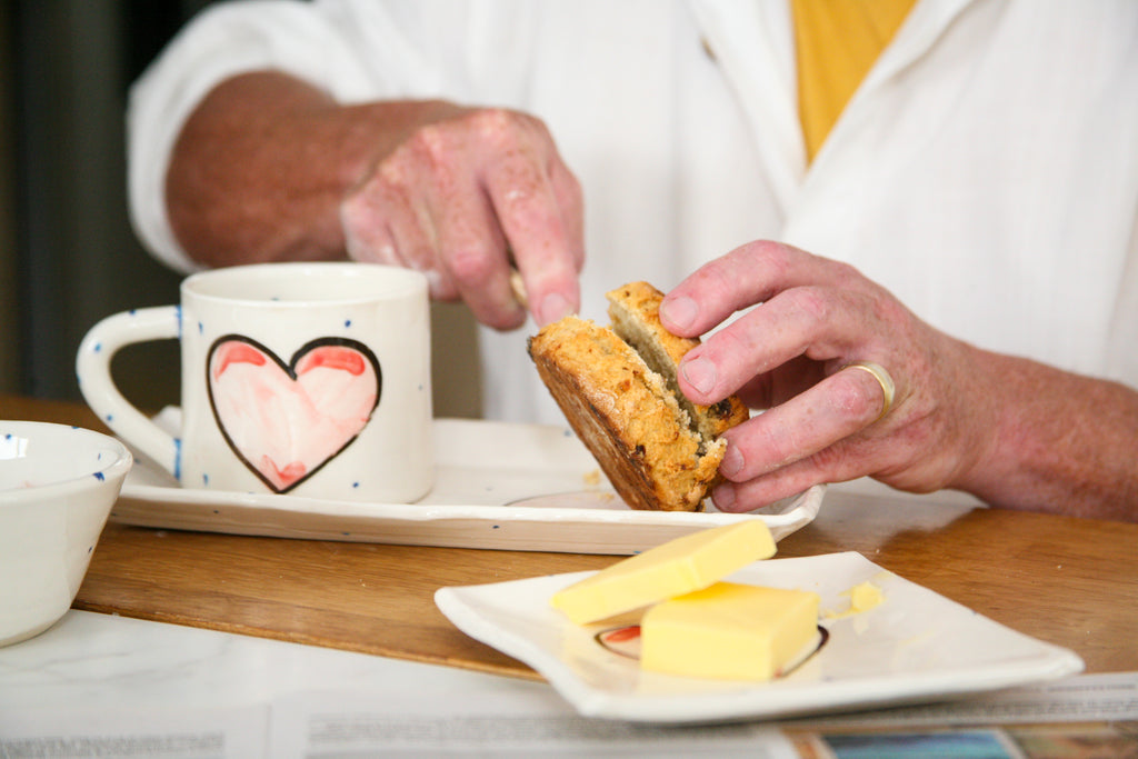 Person cutting a pastry with a heart-themed mug and plate on a table