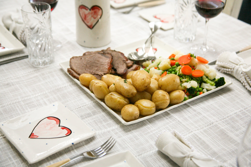 Serving dish with hand painted hearts serving potatoes, meat and veg.