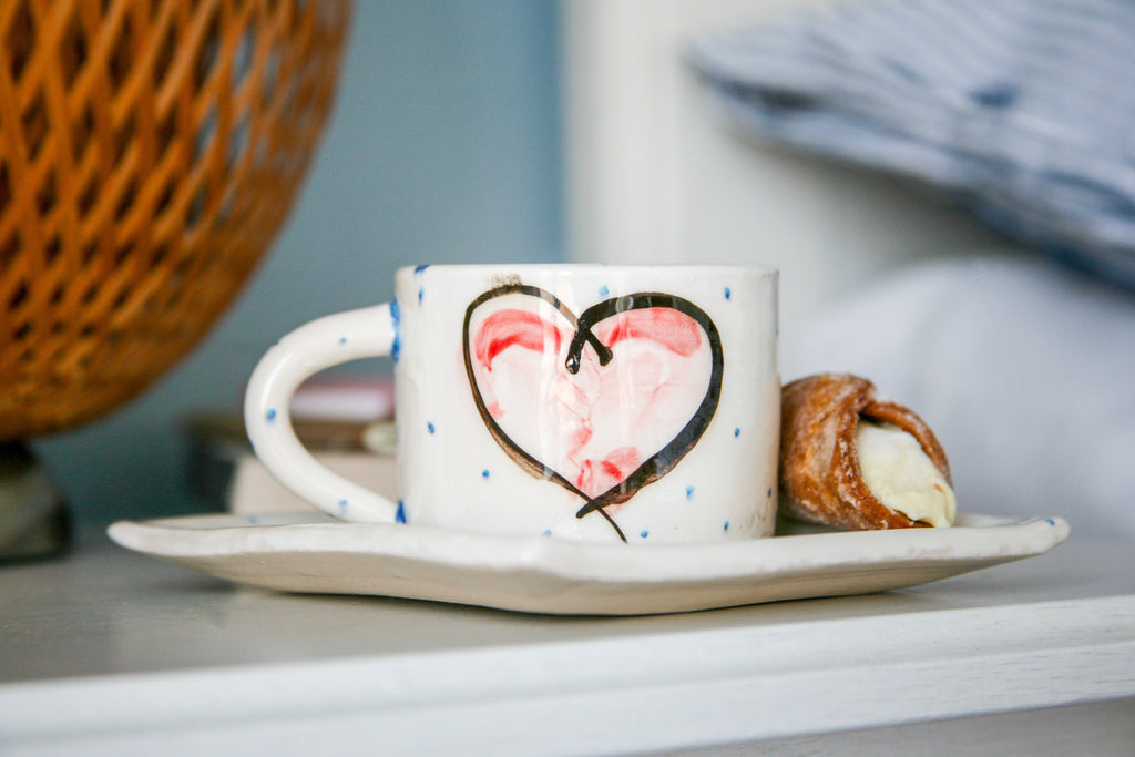 Unique ceramic gift set, perfect for coffee and tea lovers, made up of one mug and one side plate that acts as a saucer, hand painted with pink heart design.