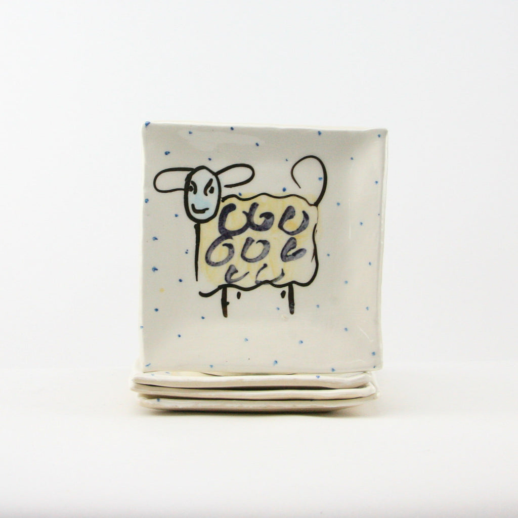 Contemporary Ceramic Set of four side plates that are handmade and hand painted with  humorous sheep, periodic blue polka dots on a luxurious white glaze.  