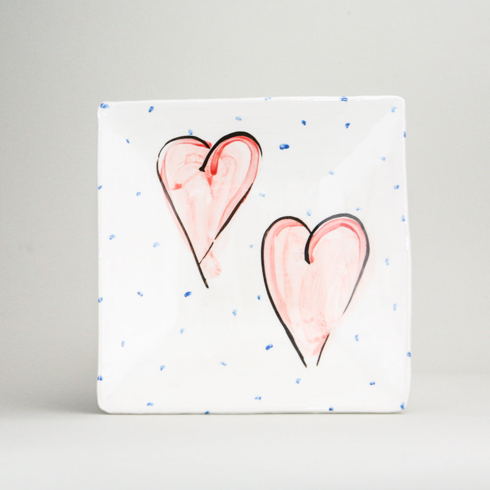 White earthenware square platter hand-painted with blue dots and two red hearts with black outlines. Handmade in Ireland.
