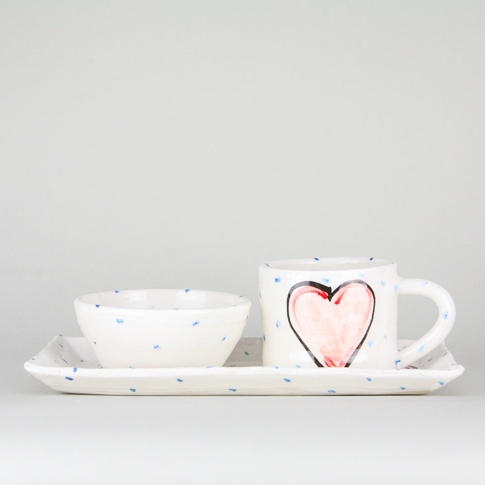 Red Grá Heart rectangular platter and mug set. The mug sitting on the right heart of the platter and handle facing right. Blue dots pepper the handmade Irish pottery. A coordinating ramekin bowl rests on the left side of the platter.