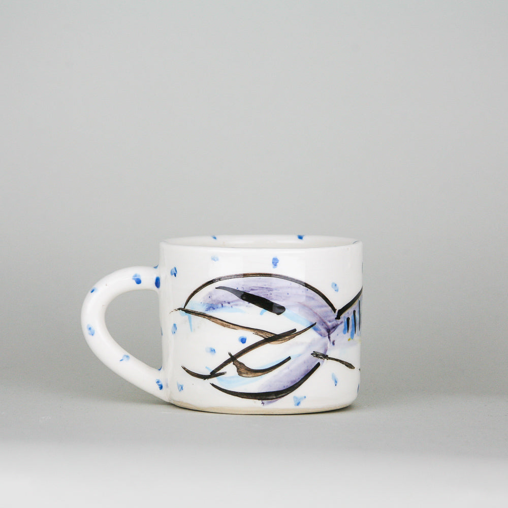 A handmade pottery mug. Crisp white Irish pottery with little blue dots hand-painted along with a smiling mackerel fish.