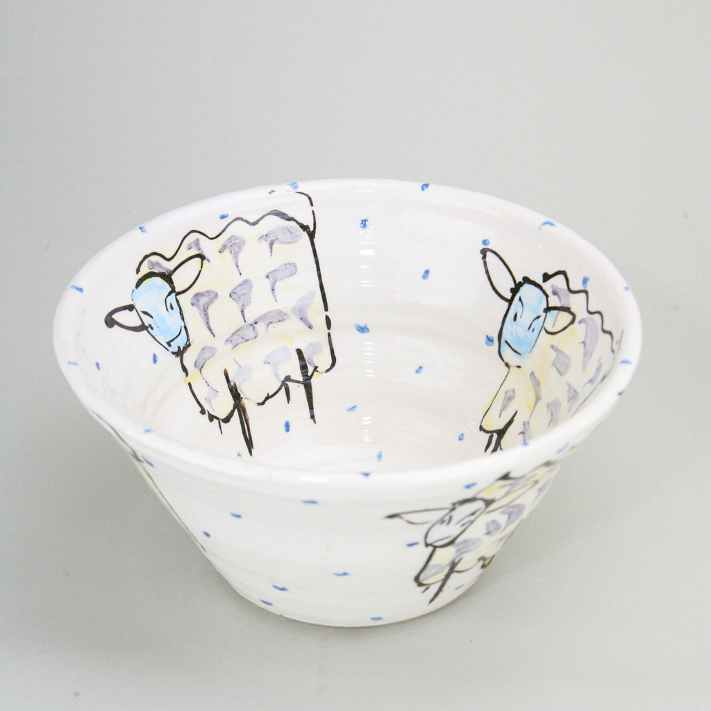 Sheep hand-painted on the inside and outside of a bowl with blue dots peppering the white Irish ceramic pottery. Handmade in Ireland.