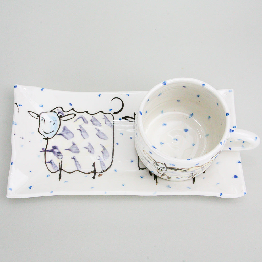 Witty sheep rectangular platter and mug set. The mug sits on the right side of the platter and handle facing right. Blue dots pepper the handmade Irish pottery. 