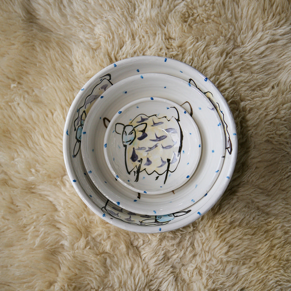 Three sizes of bowls nested together, from the ramekin to the small bowl, medium bowl, and the large bowl. Each is hand-painted with the sheep motif unique to Charlie Mahon. Handmade in Ireland.